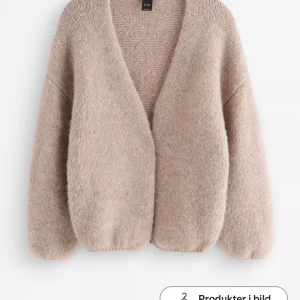 Beige stickad kofta Lindex - Mysig beige oversized kofta med djup V-ringning och ballongärmar. Koftan är stickad i ett mjukt material och har en avslappnad passform utan knappar. Perfekt för lager på lager och en chill look. Xs/S