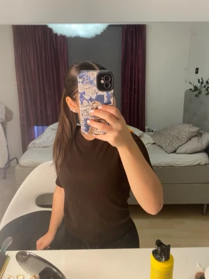 Svart ribbad kortärmad topp - En enkel och stilren svart ribbad topp med korta ärmar och rund hals. Perfekt att matcha med jeans eller kjol för en clean look. Sitter snyggt och har en klassisk passform.