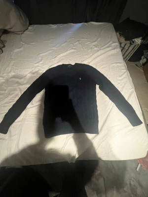 Mörkblå stickad tröja Polo Ralph Lauren - Säljer en mörkblå stickad cable knitted från Polo Ralph Lauren med klassisk kabelstickning och rund hals. Tröjan har ett litet broderat logomärke på bröstet och långa ärmar. Perfekt för dig som gillar stilrena och tidlösa plagg. pris går att diskutera