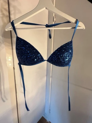 Blå glittrig bikiniöverdel med snörning - Snygg blå bikiniöverdel med glittriga paljetter på framsidan. Klassisk trekantsmodell med knyt i nacken och ryggen för justerbar passform. Perfekt för dig som vill sticka ut på stranden eller vid poolen. Från calzedonia i modellen cobey❤️