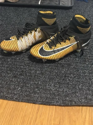 Nike Mercurial fotbollsskor  - Säljer ett par nike mercurials med hög strumpa. Skorna är ett par klassiker som passar perfekt till alla. Ett par väldigt ovanliga skor. Perfekta för dig som vill sticka ut på matchen. Tveka inte med å höra av dig vid frågor eller bilder! Priset är ej hugget ur sten!