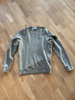 Grå sweatshirt från Stone Island - Snygg grå sweatshirt från Stone Island. Knappt använt. Får till extra knapp osv. Väldigt bra skick och äkta(Finns tagg ). Skriv om ni har frågor!!! Pris ej hugget i sten.