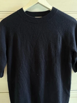 Mörkblå stickad tröja med kort ärm - Säljer en trekvartsärmad marinblå tröja. Materialet är stickat men tröjan är inte stickig. Inte kommit till användning. PostNord prioriteras