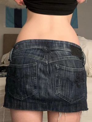 Mörkblå jeanskjol med rå kant - Trendig mörkblå jeanskjol i kort modell med rå, fransig kant nertill. Kjolen har klassiska fickor både fram och bak samt bälteshällor. Perfekt för dig som gillar en avslappnad och edgy stil. 40cm raktöver midjan❤️