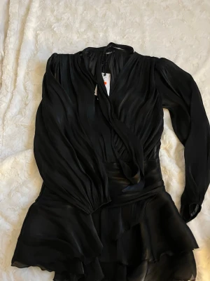 Klänning - Klänning från Gina tricot aldrig använd. Fina volanger och snöre runt halsen som går att knyta. Fina ballongärmar. Stl 38