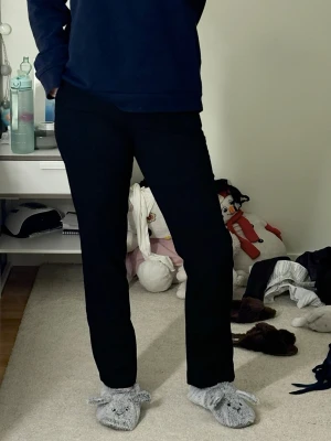 Svarta raka kostymbyxor - Säljer ett par svarta kostymbyxor med rak passform och hög midja. Byxorna har klassisk design utan synliga detaljer och är perfekta för en clean och stilren look. Materialet känns mjukt och följsamt, vilket gör dem bekväma att bära hela dagen.