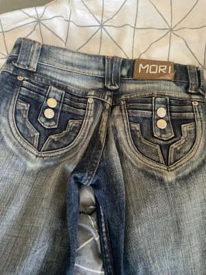 2000s Blå raka jeans - Säljer ett par blå Lågmidjade jeans från 2000s med raka ben . Jeansen har riktigt snygga bak fickor och passar perfekt till dig som vill ha en liten extra look, dom är som nya och är hela och fina innebens längden är 66 och hela byxan är 85 