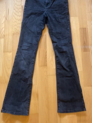 Svarta utsvängda jeans - Snygga svarta jeans med utsvängda ben och klassiska bakfickor. Jeansen är tillverkade i ett stretchigt denimtyg som sitter skönt. Perfekta för dig som gillar en retroinspirerad look.