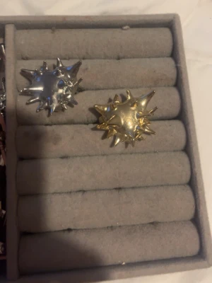Två spikiga statementringar - Säljer två coola statementringar med spikig design, en i blankt silverfärgat metall och en i guldton. Perfekta för dig som vill sticka ut och addera en edgy touch till din stil. Runda ringar med stora, tredimensionella former och metallisk finish.