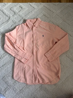 Ralph Lauren Skjorta – Ljusrosa - Ralph Lauren Skjorta – Ljusrosa 👔 Storlek: M 🩷 Färg: Ljusrosa 🔄 Skick: 8/10 – använd men i fint skick 💎 Märke: Polo Ralph Lauren 