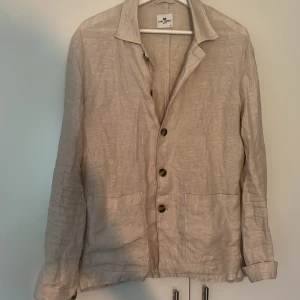 Beige linnejacka från John Henric - Säljer en snygg beige linne overshirt från John Henric. Perfekt för vår och sommar med sin lätta och luftiga känsla. Jackan har en klassisk krage och knappar framtill. Den är i storlek M : Pris 799 Skick: 9/10