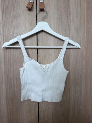Vit ribbad topp från H&M - Vitt linne från H&M med hjärtformad urpingning. Använd 1 gång
