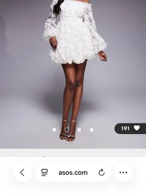 Vit broderad miniklänning ASOS LUXE - otroligt fin vit studentklänning från ASOS LUXE med broderade 3D-blommor och ballongärmar. Klänningen har offshoulder-modell och markerad midja, perfekt för dig som vill sticka ut. Den är helt oanvänd. Nypris är 1367 kr. 