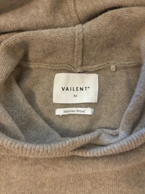 Beige hoodie i merinoull från Vailent - Snygg beige hoodie från Vailent i mjuk merinoull. Klassisk modell med huva och ribbade muddar vid ärmslut och nederkant. Perfekt för dig som gillar stilrena och bekväma plagg med premiumkänsla.