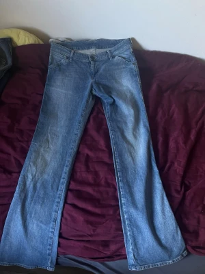 Blå lågmidjade bootcut jeans  - Säljer ett par klassiska blå bootcut jeans med låg midja i storlek S från wrangler