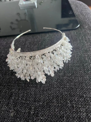 Silverfärgat diadem med kristallpärlor - Unikt diadem i silverfärg dekorerat med mängder av gnistrande kristallpärlor i olika former. Diademet har en lyxig och iögonfallande design med pärlor som liknar små grenar. Perfekt för dig som vill sticka ut och addera extra glamour till din look.