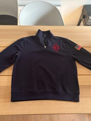 Epstein quarter zip  - Säljer en marinblå populär quarter zip med amerikanska flaggan på vänster arm. Tröjan är helt oanvänd! Storlek: M