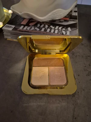 Highlighterpalett i guld från Tom Ford - Lyxig highlighterpalett från Tom Ford med tre skimrande nyanser i champagne, guld, rosé och koppar. Kommer i en elegant fyrkantig förpackning med vit ovansida och guldfärgad insida. Perfekt för att skapa glow och highlighta ansiktet. Lyxig, lyxförpackning! Swatchad/testad. Fint skick.