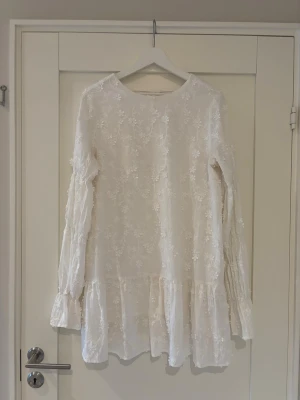Vit klänning från NA-KD   - Säljer en jättefin vit klänning från NA-KD i storlek 38. Klänningen har vackra vita blomdetaljer och långa ballongärmar som ger en elegant och romantisk känsla. Perfekt till fest, student, bröllopsgäst eller sommarkvällar. Bara använt 2 gånger. 600 kr men kan gå ner!