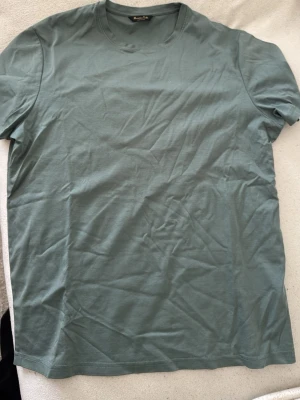 Grön t-shirt från Massimo Dutti - Snygg grön t-shirt från Massimo Dutti i mjuk bomull. Klassisk rund halsringning och korta ärmar. Perfekt basplagg med enkel och stilren design.