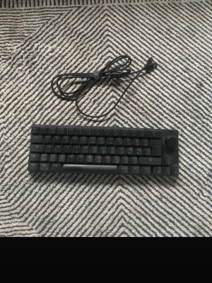 Loop mekaniskt tangentbord svart - Säljer ett kompakt svart mekaniskt tangentbord från Loop med USB-kabel. Tangentbordet har en rund volymratt i hörnet och en minimalistisk design. Perfekt för dig som vill ha ett stilrent och smidigt tangentbord till datorn.
