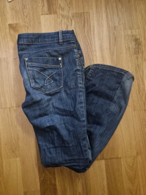 Lågmidjade mörkblåa jeans - Lågmidjade dark wash jeans  Var originellt skinny men har sytts om till bootcut  De har kardborrband istället för dragkedja men det funkar lika bra Väldigt fin design på fickorna  Inga skador  Pris kan diskuteras!