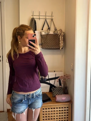 Mörklila långärmad topp från H&M - En basic långärmad topp från H&M i mörklila färg. Tillverkad i mjuk ekologisk bomull med rund halsringning och normal passform. Perfekt att styla med jeans eller kjol för en enkel och snygg look.