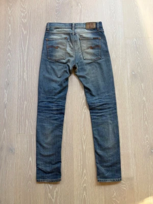 Ljusblåa Nudie jeans - W28 - Säljer ett par riktigt snyggt slitna Nudie Jeans i modellen Lean Dean Storlek 28/32 | Skick 7/10 | Det finns 2 små hål i skrevet som går att se på sista bilden (se bild 7), inget som är superallvarligt och går självklart att sy 🧵 Det finns även 2 hål som är lagade på ett snyggare sätt med patches (se bild 5 och 6) Kom gärna med frågor eller prisförslag 💬