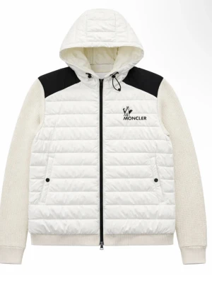 Vit pufferjacka med huva från Moncler - Snygg vit pufferjacka från Moncler med svarta axelpartier och logga på bröstet. Jackan har stickade ärmar, dragkedja framtill och två fickor med knappar. Perfekt för kalla dagar med sin vadderade design och huva.