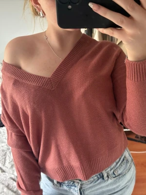 Rosa omlott stickad klänning - Trendig rosa stickad klänning med omlottkänsla och v-ringad hals. Modellen är croppad och har långa ärmar. Perfekt för dig som gillar en avslappnad men snygg stil.