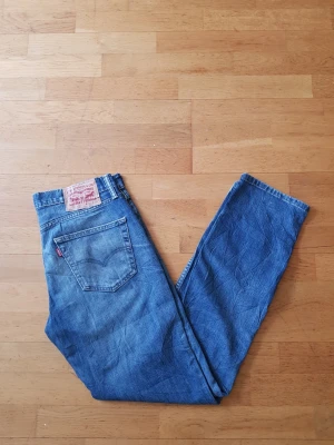 Levi's 511  - Säljer ett par klassiska blå Levi's 511 jeans i slim fit-modell. Jeansen har fem fickor, normalhög midja och är tillverkade i slitstark denim. Perfekta för dig som gillar en tidlös och avslappnad stil.