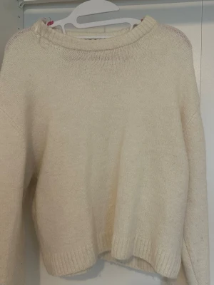 Vit  stickad tröja i ullmix - Mysig vit stickad tröja med rund hals och långa ärmar. Tröjan har ribbstickade muddar vid hals, ärmslut och nederkant. Perfekt för lager på lager och enkel att matcha till olika outfits.