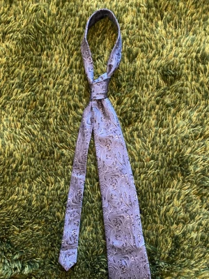 Grå/silvrig sidenslips med blommigt mönster - Säljer en snygg grå/silvrig sidenslips med elegant blommigt mönster Slipsen har en klassisk form och är tillverkad i ett glansigt siden som ger en lyxig känsla. Perfekt för dig som vill addera lite extra stil till outfiten.