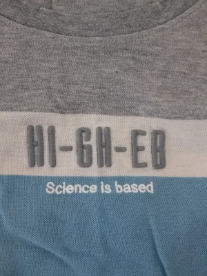 Grå och blå t-shirt med tryck - T-shirt i grått, vitt och ljusblått med texten 'HI-GH-EB' och 'Science is based' på bröstet. Klassisk rund hals och korta ärmar. Perfekt för dig som gillar en avslappnad och cool stil.