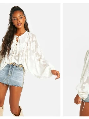 Vit blus med ballongärmar och knyt - Trendig vit blus med transparent mönster, voluminösa ballongärmar och knytning fram i halsen. Blusen har en avslappnad passform och är tillverkad i ett lätt, luftigt material som ger en romantisk känsla. 