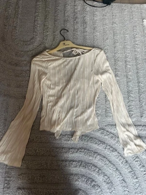 Beige omlottopp med knyt från Pieces - En beige fin topp med en öppen rygg från NAKD, aldrig använd. Jätte fin material och supersnygg till utekväll eller bara vardagligt!