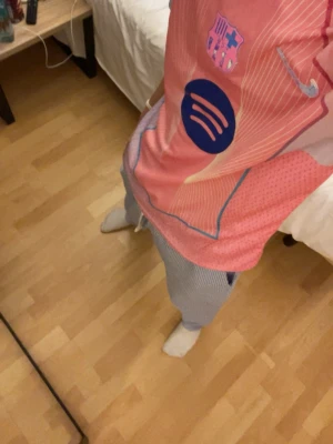 Rosa FC Barcelona matchtröja Nike - Säljer en rosa FC Barcelona matchtröja från Nike med klubbmärke och sponsorlogga på bröstet. Tröjan har blå detaljer och vita tunna ränder, samt rund hals. Perfekt för dig som älskar fotboll och vill sticka ut på planen.