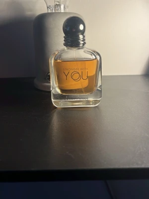 Stronger With You parfym från Armani - Stronger With You från Armani är en elegant parfym i en genomskinlig glasflaska med rundade former och svart rund kork. Perfekt för dig som gillar exklusiva dofter. Jag har inte använt den så mycket, det är ungefär 40-45ml kvar skulle jag gissa på.🔥🔥🔥 Förpackningen har jag inte.