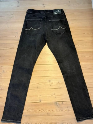 Svarta jeans från Jacob Choën  - Ett par fina Jacob Choen Jeans i svart färg med en svart läderlapp baktill. Några små trådar som släppt något i övrigt bra skick. Byxorna är Slim Fit W32 Längd på  Byxben är 104 cm, Övre delen av låret 25 cm, midje mått 37 cm. Kontakta oss vid frågor!  Skickas samma dag eller dagen efter, därefter 1-3 dagars leveranstid! P2 