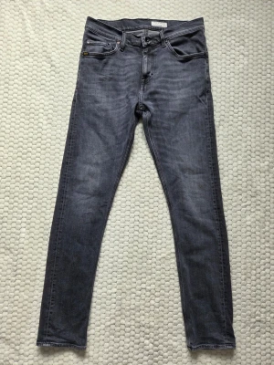  Jeans från Tiger of Sweden - Säljer dessa snygga gråa jeans från Tiger of Sweden. De har passformen slim fit med storleken W29/L32. De är fortfarande i väldigt bra skick med inga synliga skador. De har en urtvättad look från fabrik och är riktigt bekväma då de är lite stretchiga. Pris kan självklart diskuteras!