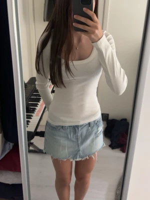 Vit långärmad topp Gina Tricot - Säljer en vit ribbad långärmad topp från Gina Tricot. Toppen har en snygg, tight passform och en djup, rundad ringning. Perfekt att styla med jeans eller kjol för en clean look.