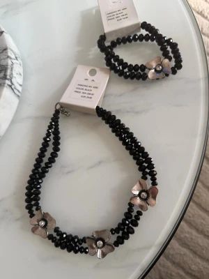 Smyckesset med svarta pärlor - Vackert smyckesset med matchande armband och halsband i svarta pärlor. De silverfärgade detaljerna ger en elegant och tidlös känsla som passar både till vardags och vid festligare tillfällen.