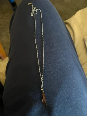 Halsband i rostfritt stål med spetsig berlock - Snyggt halsband i silverfärgat rostfritt stål med en unik, spetsig berlock. Kedjan är tunn och stilren, perfekt för att ge din outfit en cool touch. Berlocken har en modern, geometrisk form som sticker ut och passar dig som gillar minimalistiska accessoarer.