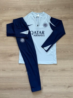 💙Nike Inter träningsset blå/ljusblå🩵 - Snyggt träningsset från Nike för Inter med långärmad tröja i ljusblått och mörkblå ärmar samt matchande byxor. Setet har Inter-logga och Qatar Airways-tryck på bröstet. Tillverkat i lätt och ventilerande material, perfekt för fotbollsträning. Passar dig som är 150-165 cm. Jag är 168 på bilden och den passar mig perfekt. Tar emot bud. Använd 1 gång. 