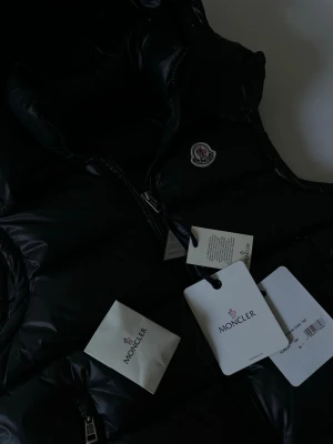 Moncler väst - Säljer min fina Moncler-väst då den tyvärr blivit för liten för mig. Västen är i mycket fint skick och knappt använd, vilket gör den till ett väldigt prisvärt alternativ.  Det är ett stilrent och mångsidigt plagg som passar perfekt under våren och hösten, men fungerar lika bra under svalare sommarkvällar.                 Hör gärna av dig vid frågor, funderingar eller om du vill lägga ett bud. Priset är inte hugget i sten.🪨😁