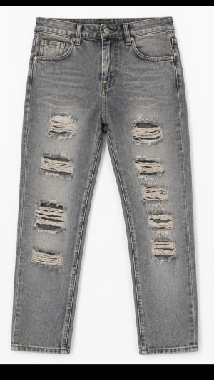 Grå slitna jeans med hål - Snygga grå jeans med slitningar och stora hål på framsidan av benen. Jeansen har klassisk femficksmodell, slim passform och är tillverkade i denim. Perfekta för en trendig och avslappnad stil.