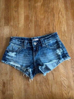 Blå jeansshorts med slitningar - Säljer ett par blå jeansshorts med slitna detaljer på framsidan från Gina Tricot 14+