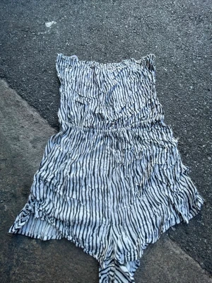 Zebramönstrad jumpsuit från H&M Divided - Säljer en luftig zebramönstrad jumpsuit från H&M Divided i storlek 36. Den har resår i midjan, tunna axelband och är tillverkad i ett mjukt, lätt tyg. Perfekt för varma dagar och ger en cool, avslappnad vibe.