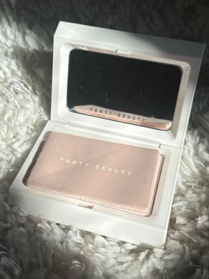 Fenty Beauty matt puder - Säljer en puder från Fenty Beauty i matt finish. Kommer i en stilren vit kompakt dosa med spegel och texten 'Fenty Beauty' på både utsidan och pudret. Färgen är UNIVERSAL och formulan är pressat puder. Perfekt för dig som vill ha en naturligt matt look.