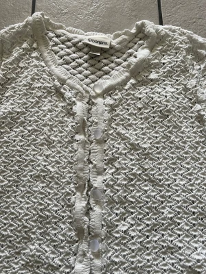 Vit virkad kofta från Bonprix storlek L - Snygg vit kofta från Bonprix med virkat mönster och rund halsringning. Koftan har knappar framtill och är tillverkad i ett luftigt, stickat material som ger en trendig och fräsch look. Perfekt att slänga över en topp för en chill outfit.